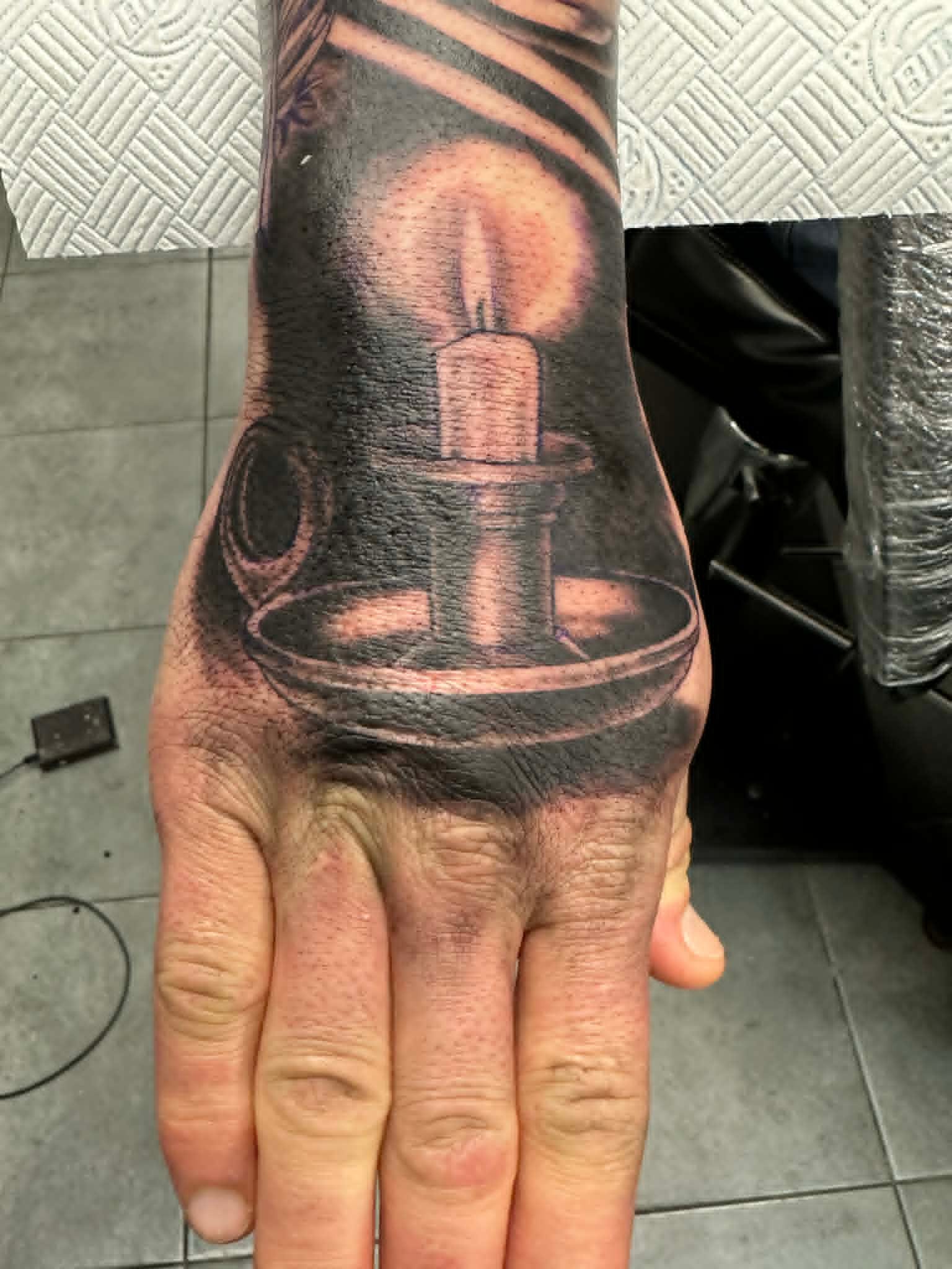 Black and grey realism lit candle hand tattoo by John Quinn at Tattoo Zone, tattoos Newcastle.