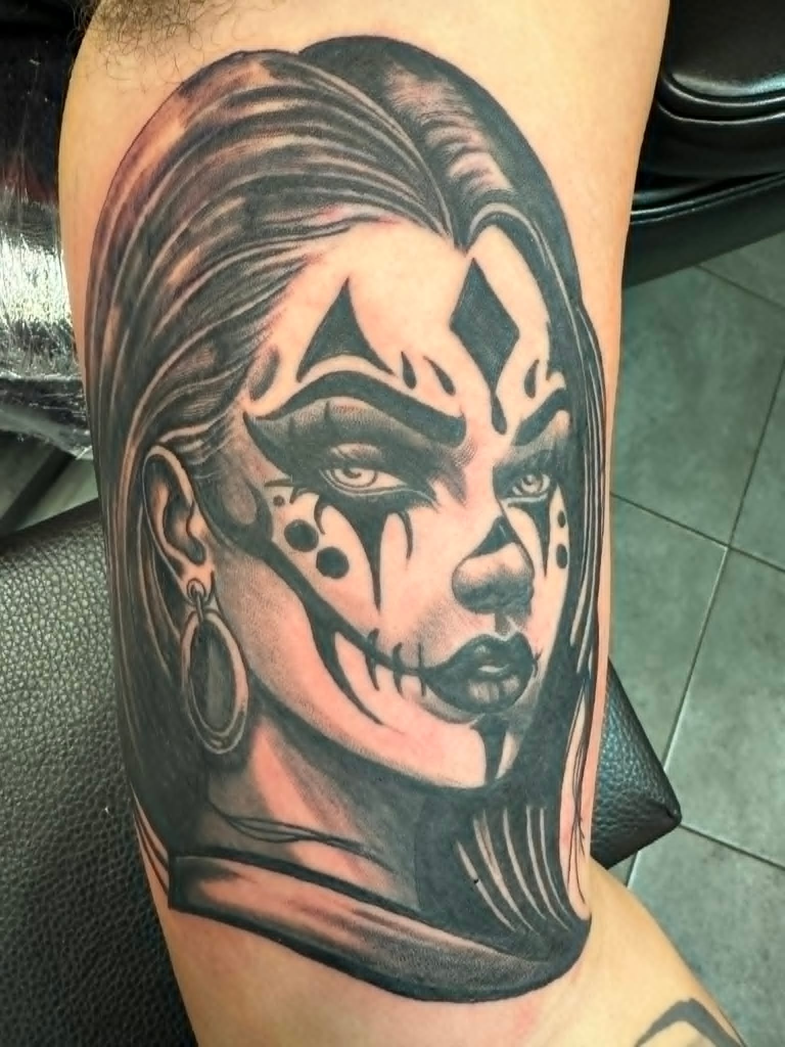Black and grey chicano payasa woman with clown face paint and hoop earring upper arm tattoo by John Quinn at Tattoo Zone Newcastle.