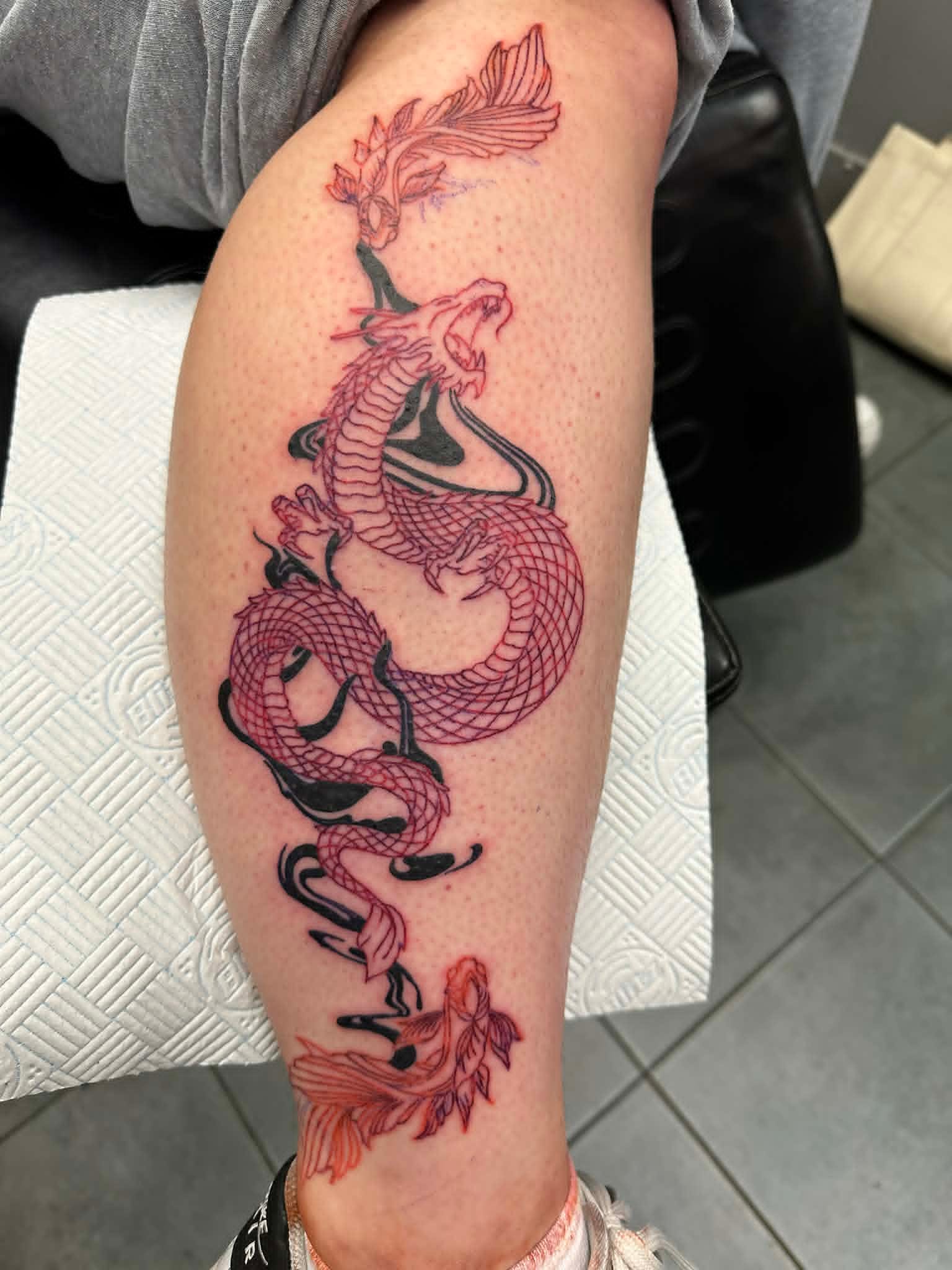 Fine line red ink dragon and koi fish calf tattoo by John Quinn at Tattoo Zone, tattoos Newcastle.