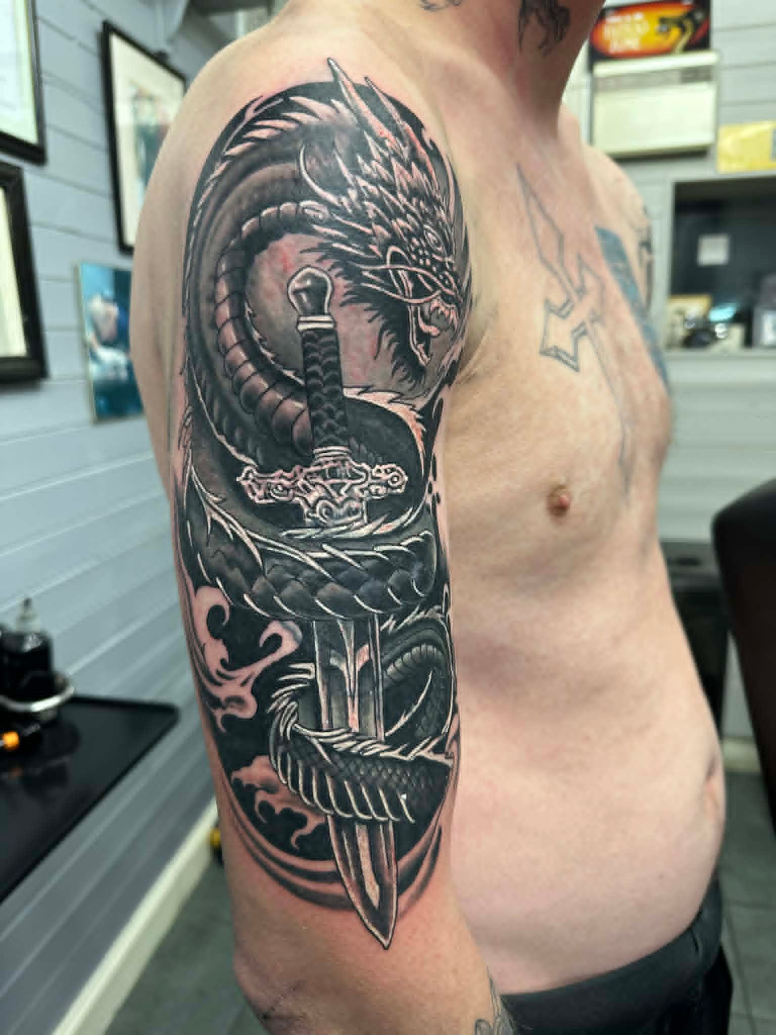 Black and grey dragon coiled around sword half sleeve by John Quinn at Tattoo Zone, tattoos Newcastle.