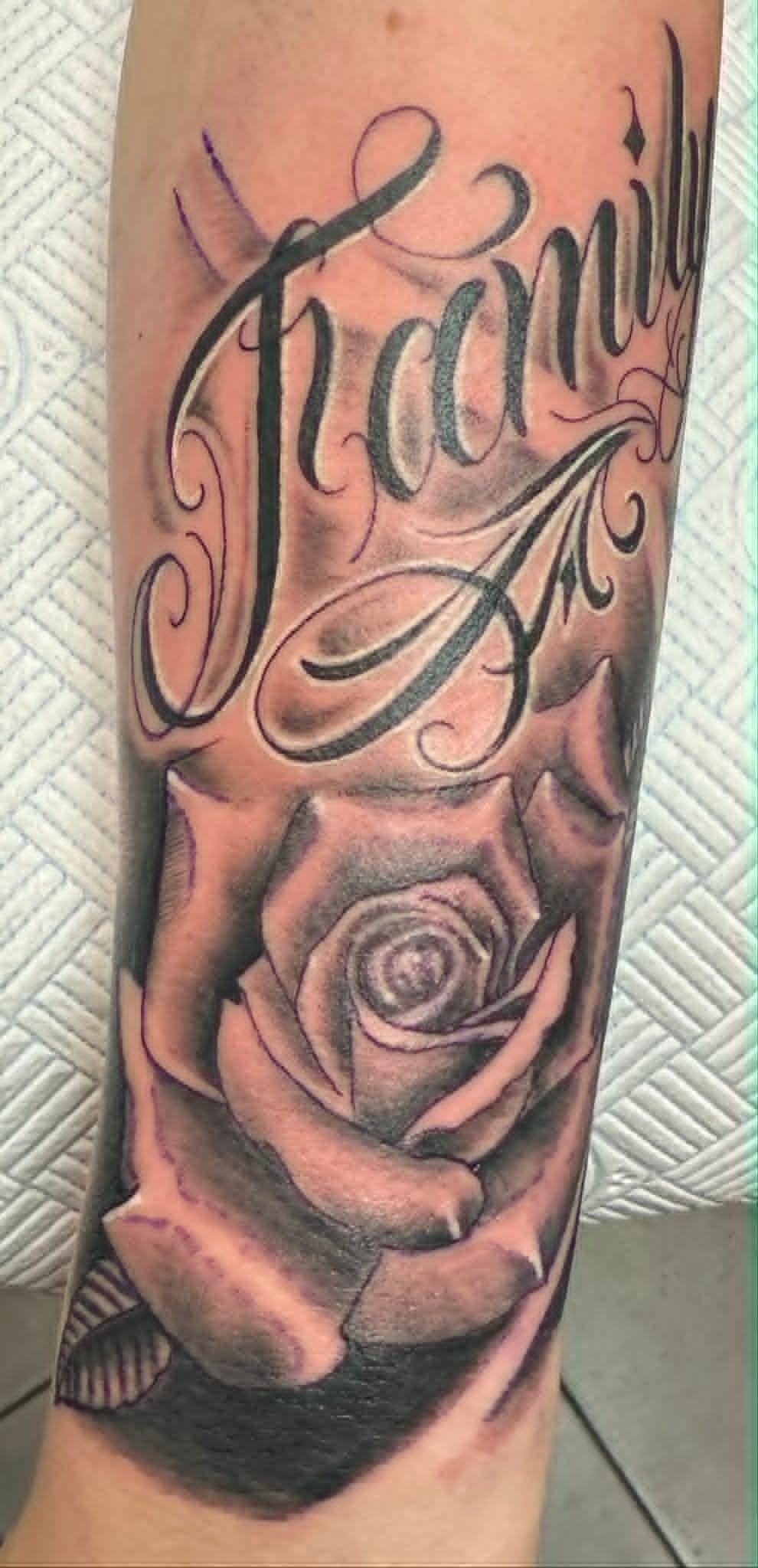Black and grey rose with Family script lettering on forearm by John Quinn at Tattoo Zone, tattoos Newcastle.