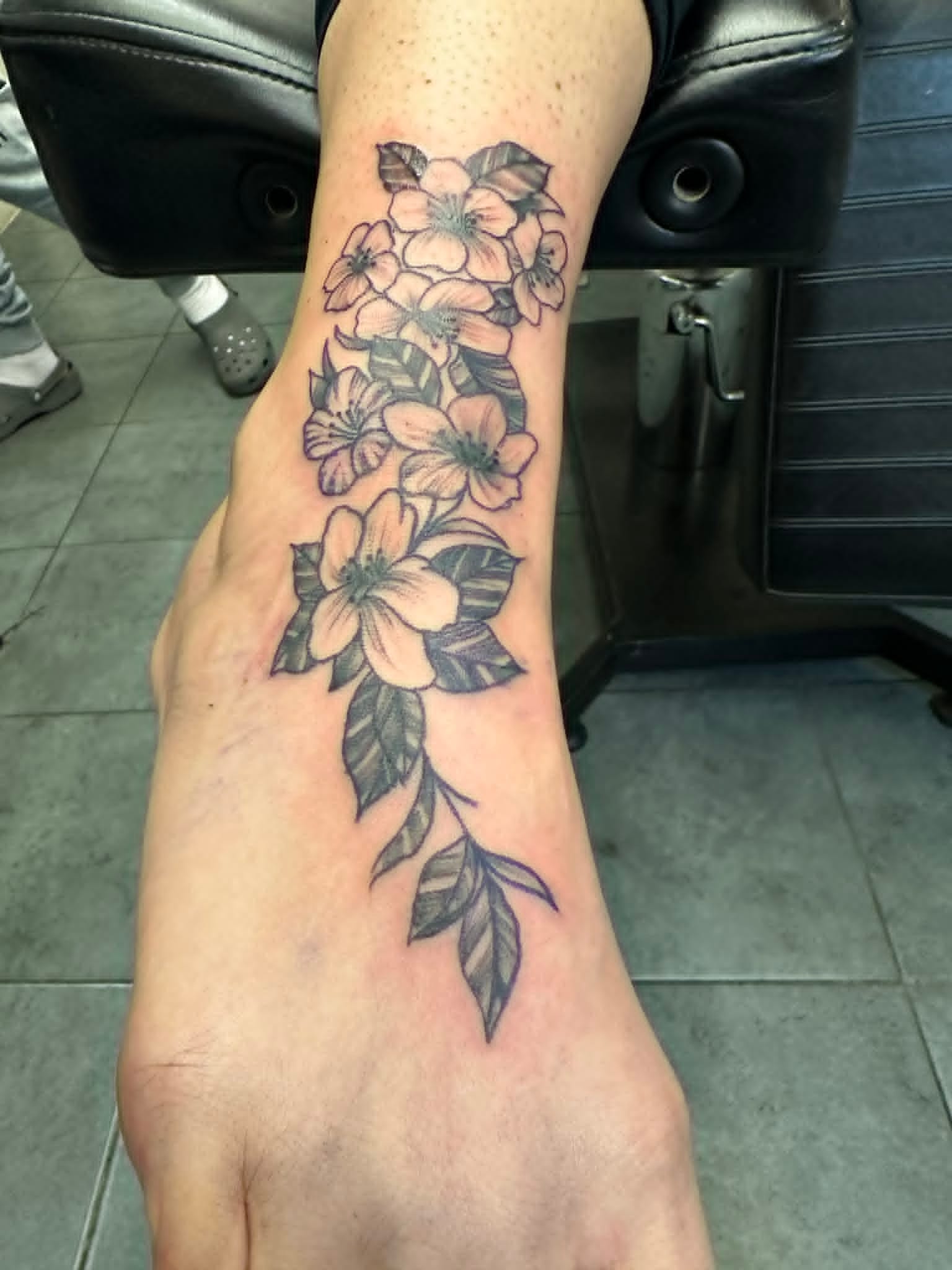 Black and grey trailing flowers and leaves on foot by John Quinn at Tattoo Zone, tattoos Newcastle.