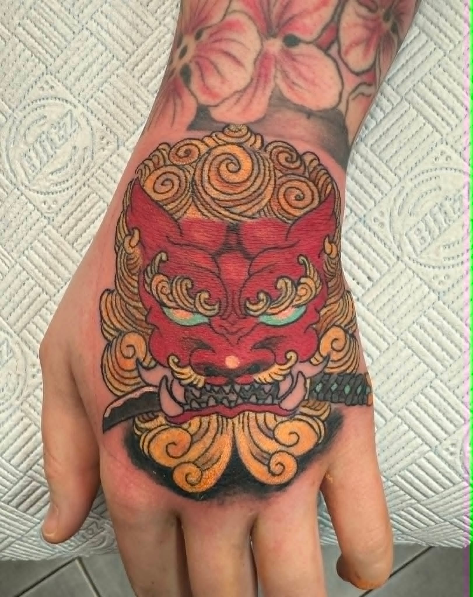 Traditional Japanese foo dog hand tattoo in red and gold by John Quinn at Tattoo Zone, tattoos Newcastle.
