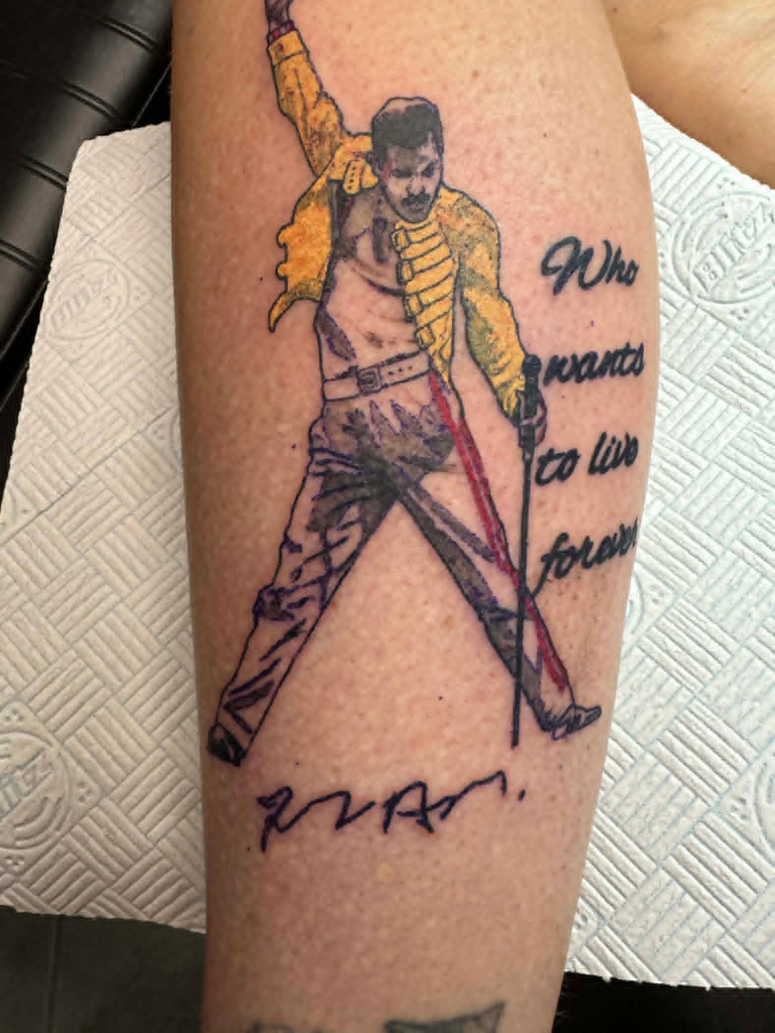 Custom Freddie Mercury portrait with Who Wants To Live Forever lyrics on the calf by John Quinn at Tattoo Zone, tattoos Newcastle.