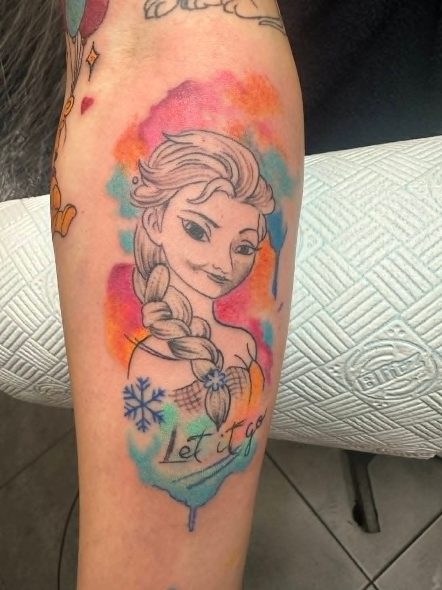 Custom Disney Frozen Elsa watercolour portrait with Let It Go script and snowflake forearm tattoo by John Quinn at Tattoo Zone Newcastle.
