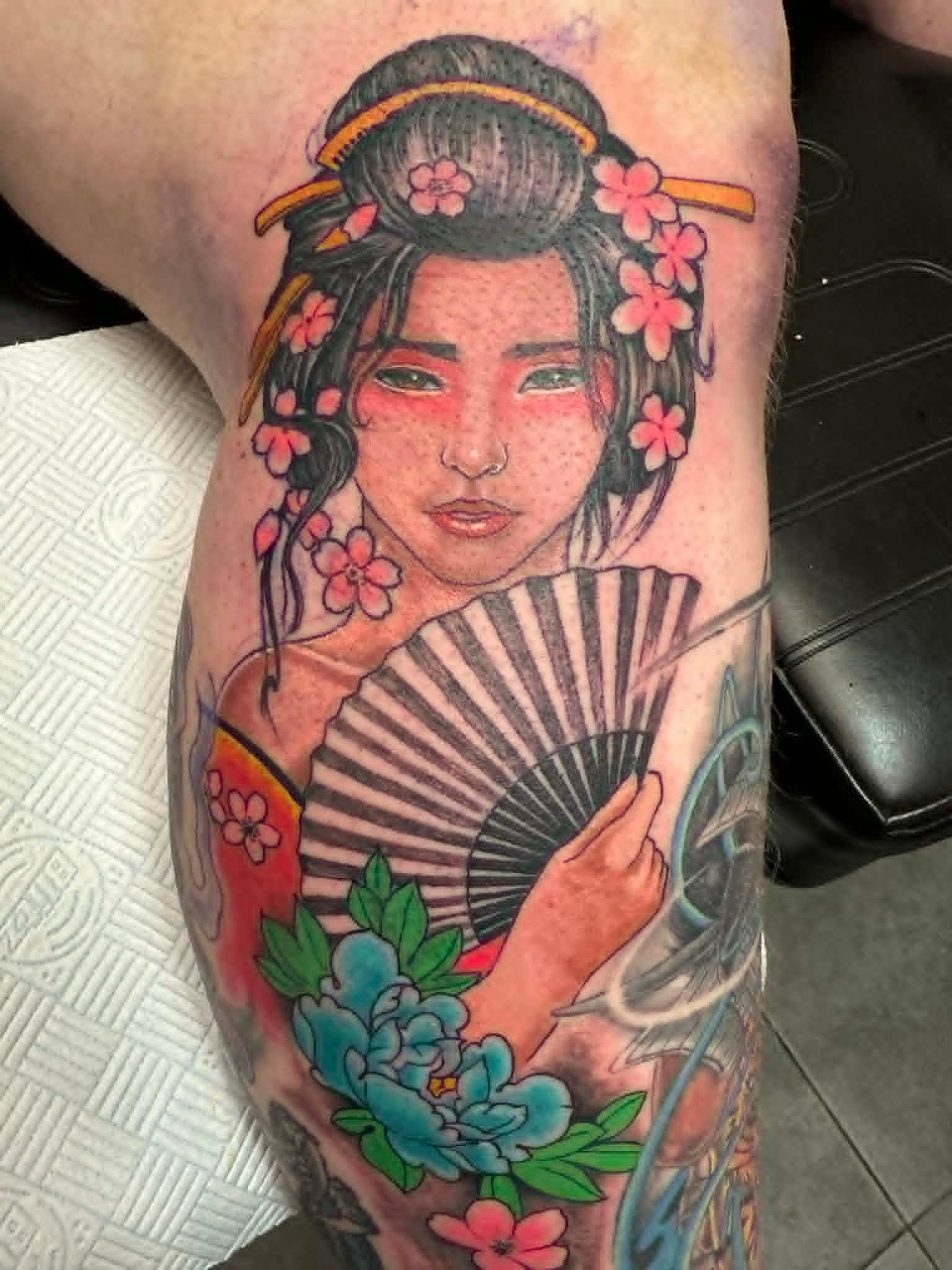 Japanese geisha with fan and cherry blossoms colour custom tattoo on thigh by John Quinn at Tattoo Zone, tattoos Newcastle.
