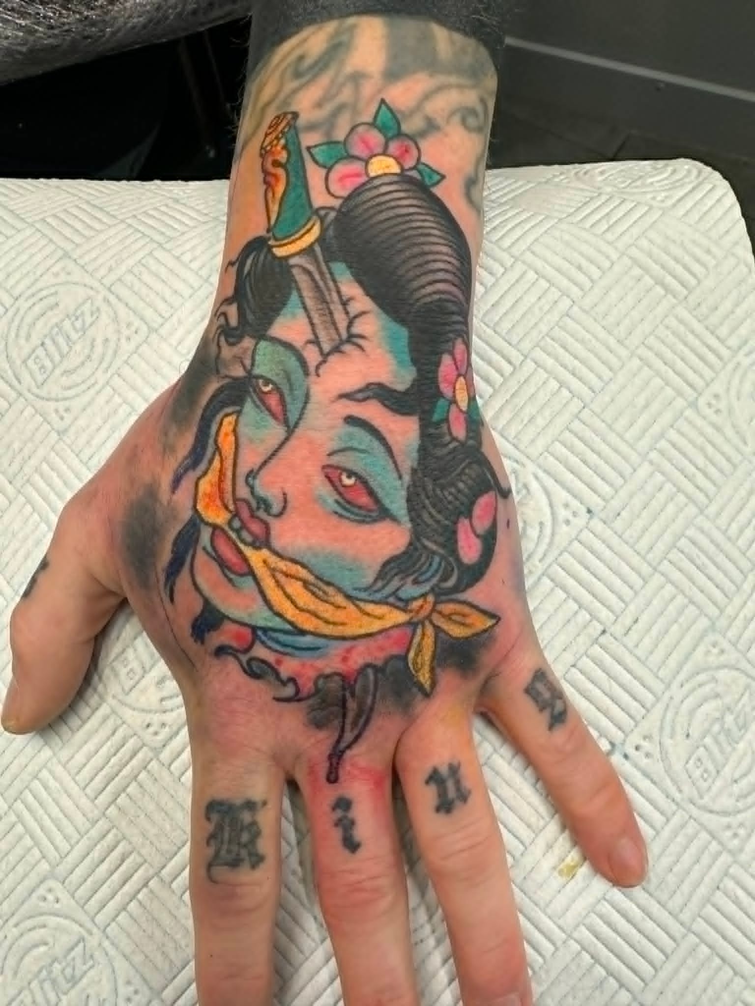 Traditional Japanese severed geisha head with dagger and cherry blossoms hand tattoo by John Quinn at Tattoo Zone Newcastle.