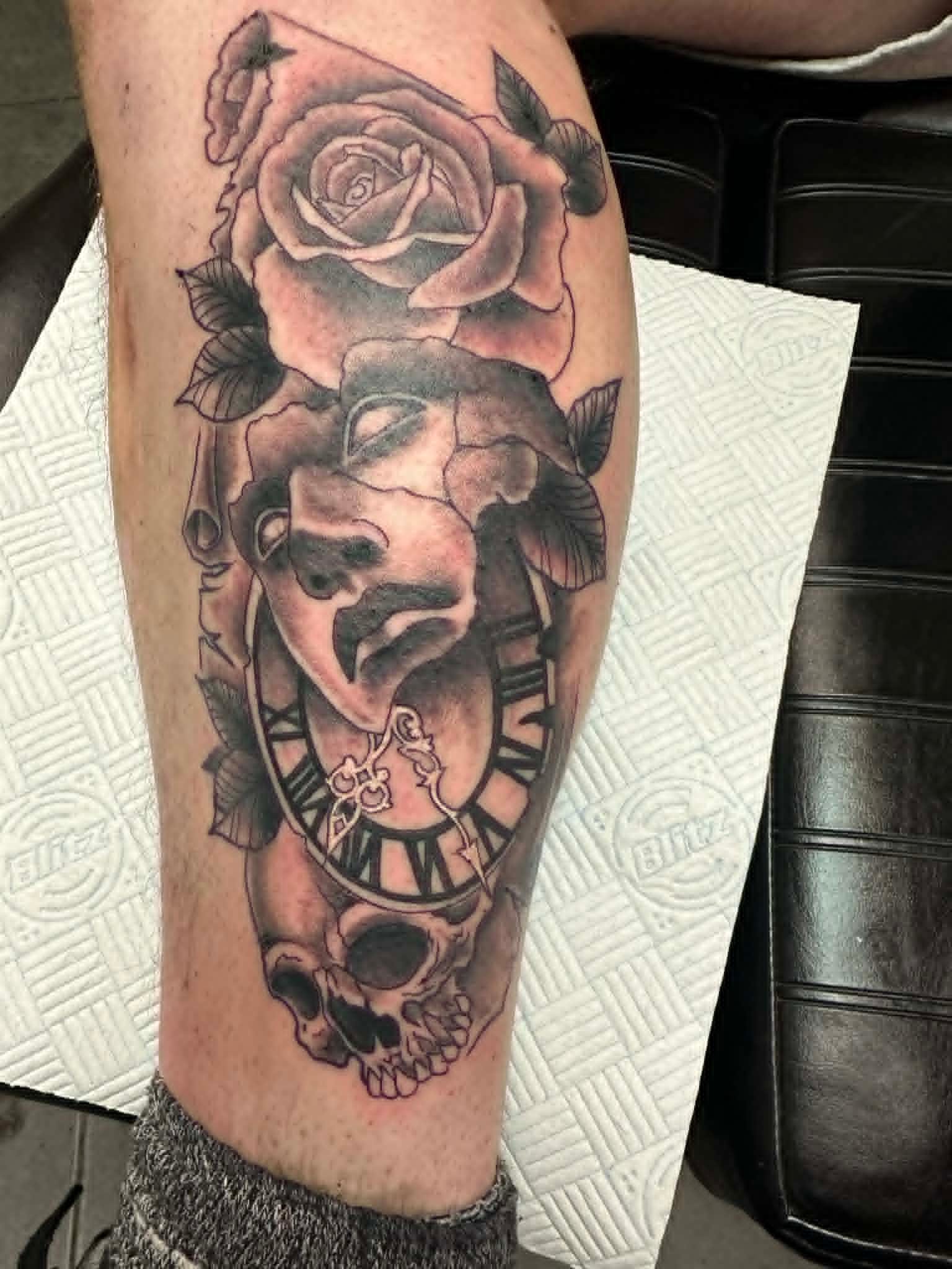 Black and grey Scream Ghostface mask with rose, Roman numeral clock and skull calf tattoo by John Quinn at Tattoo Zone Newcastle.
