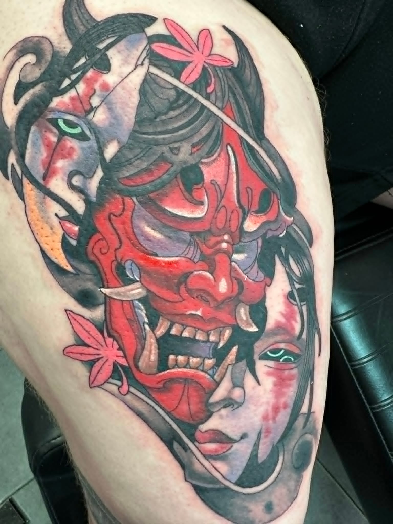 Traditional Japanese red Hannya demon mask between two geisha faces with maple leaves thigh tattoo by John Quinn at Tattoo Zone Newcastle.