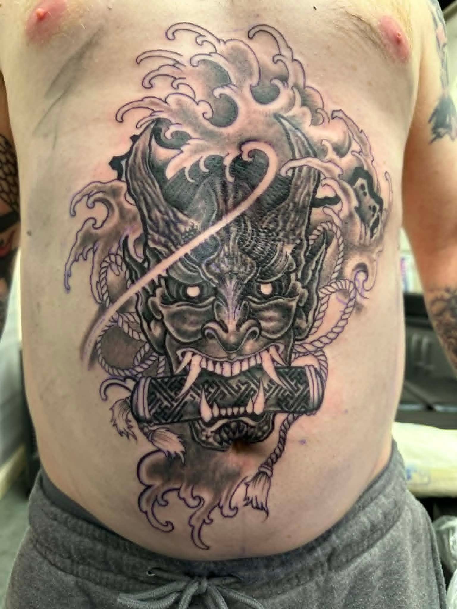 Black and grey hannya demon mask with waves on stomach by John Quinn at Tattoo Zone, tattoos Newcastle.