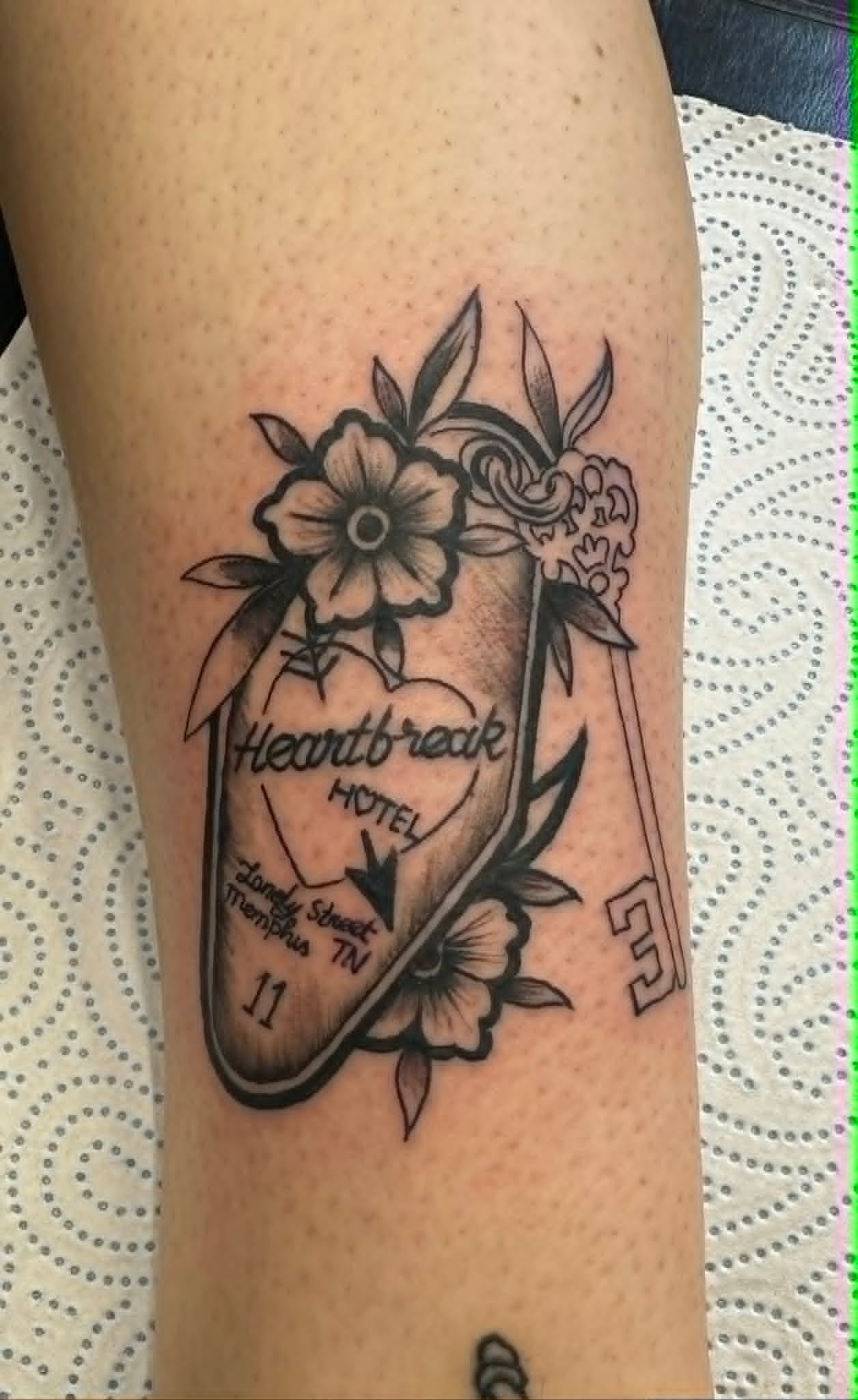 Traditional Heartbreak Hotel keychain with flowers tattoo on the arm by John Quinn at Tattoo Zone Newcastle.