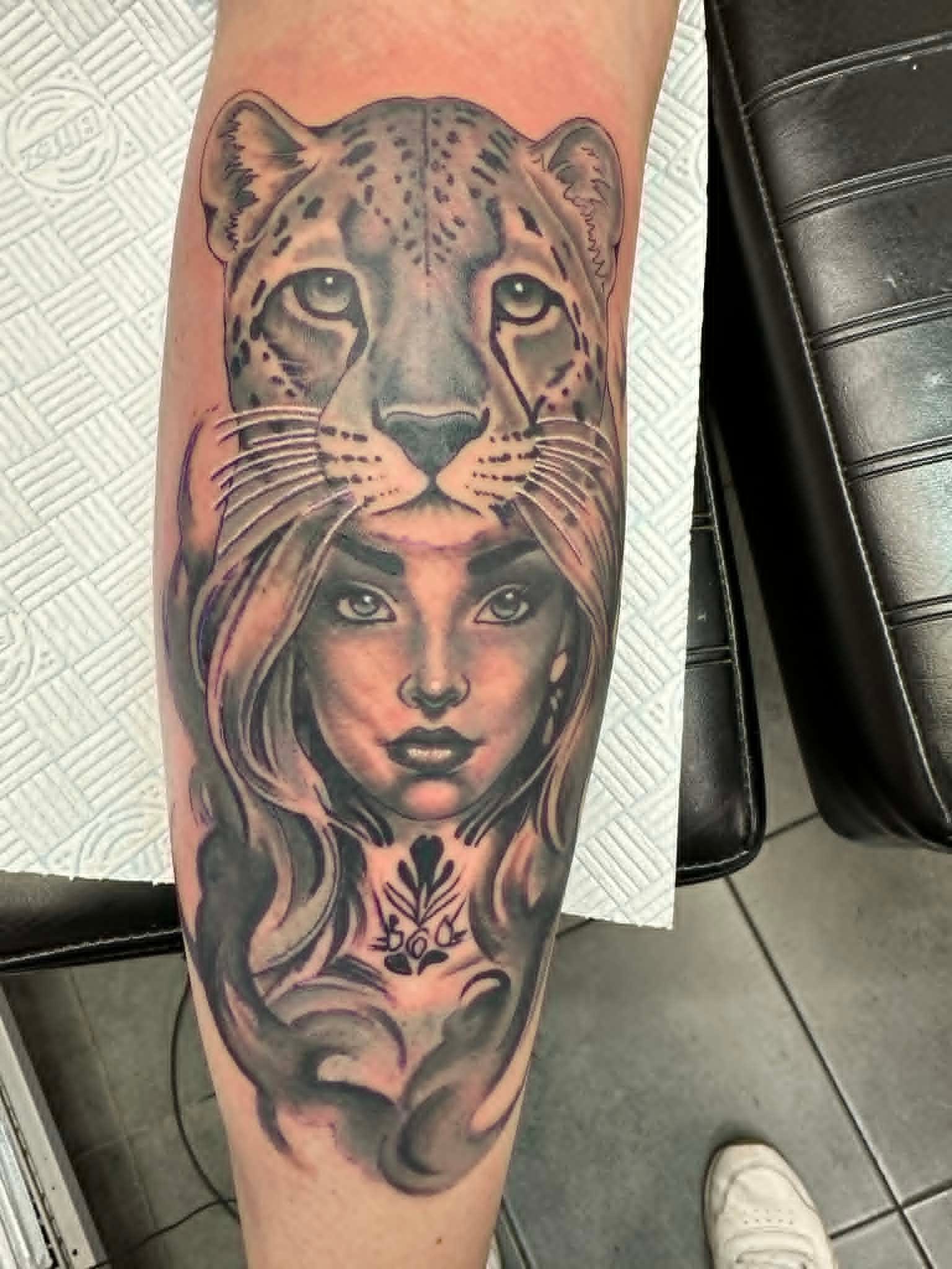 Black and grey woman with leopard headdress portrait tattoo on the calf by John Quinn at Tattoo Zone Newcastle.