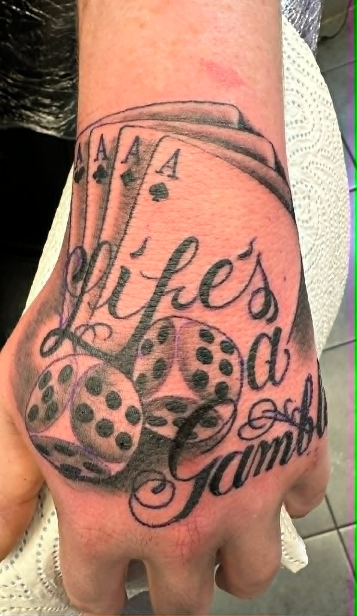 Black and grey lifes a gamble dice and aces lettering hand tattoo by John Quinn at Tattoo Zone, tattoos Newcastle.