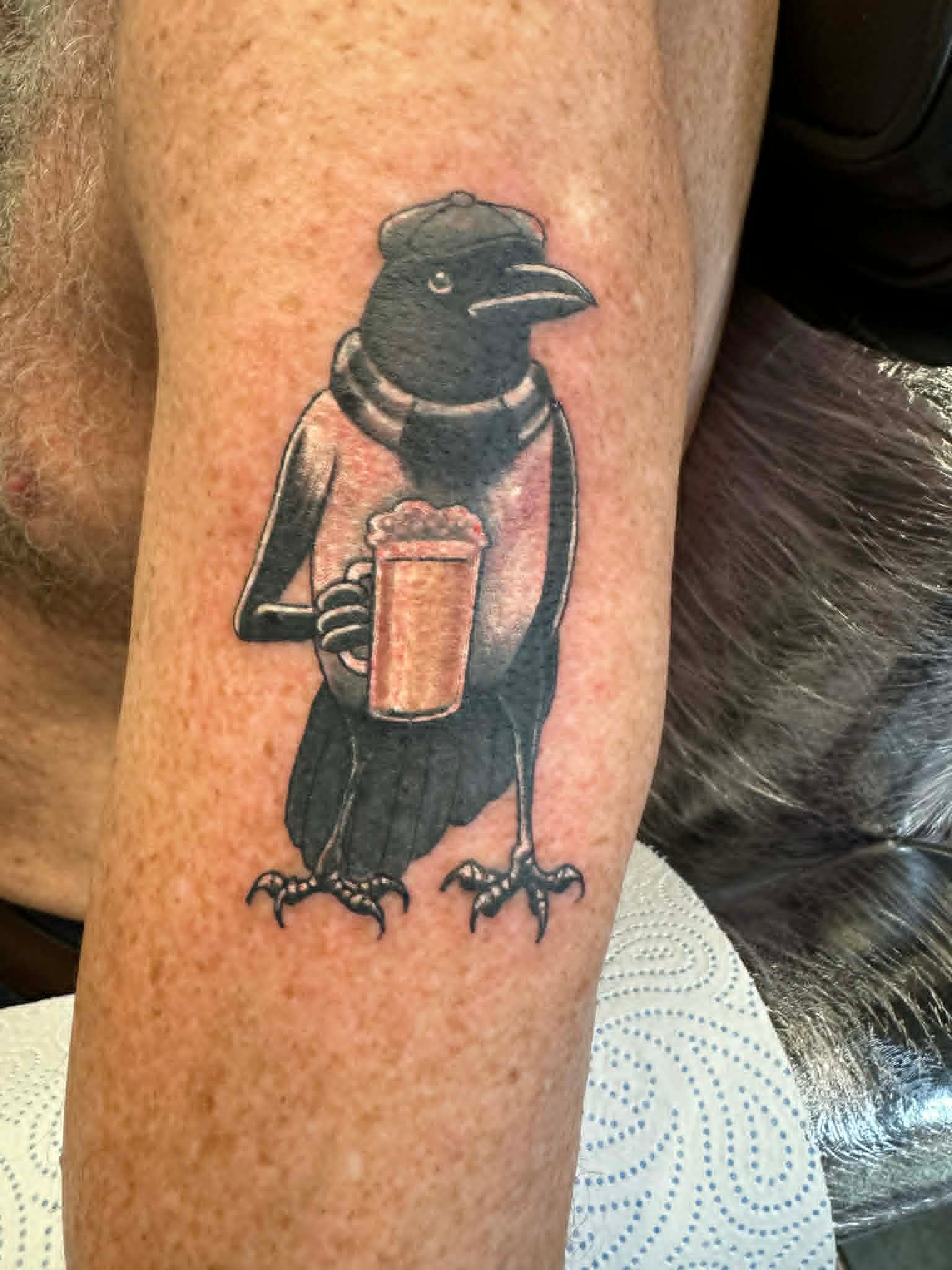 Custom magpie in flat cap holding a pint leg tattoo by John Quinn at Tattoo Zone, tattoos Newcastle.
