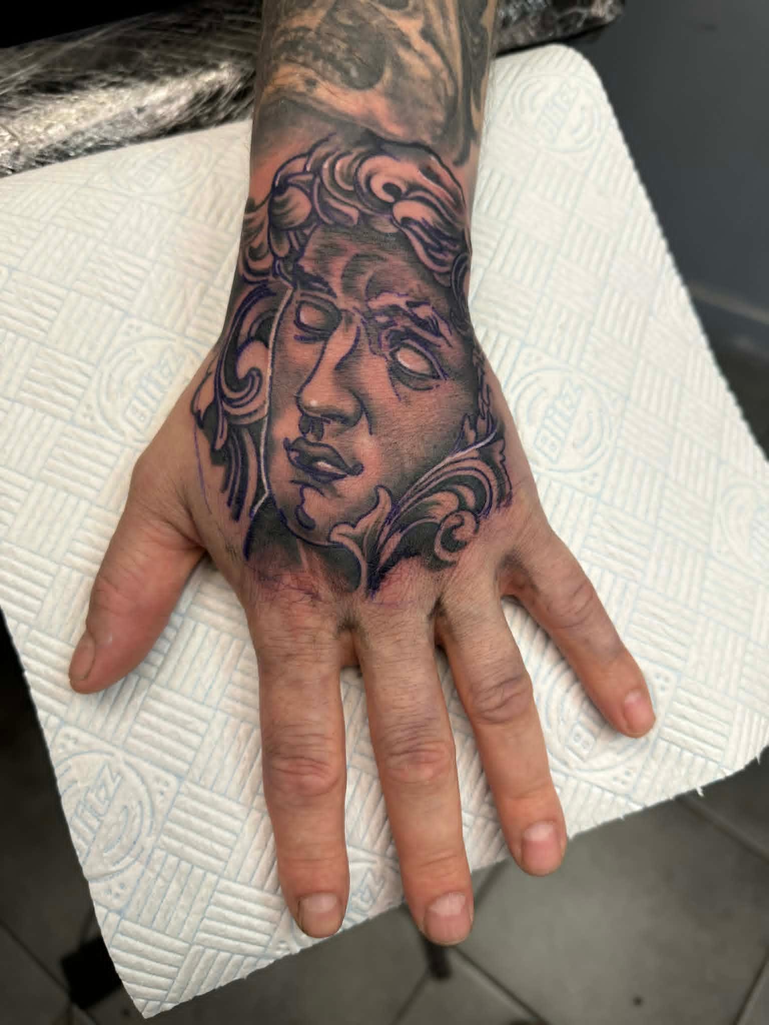 Black and grey Medusa portrait hand tattoo by John Quinn at Tattoo Zone, tattoos Newcastle.