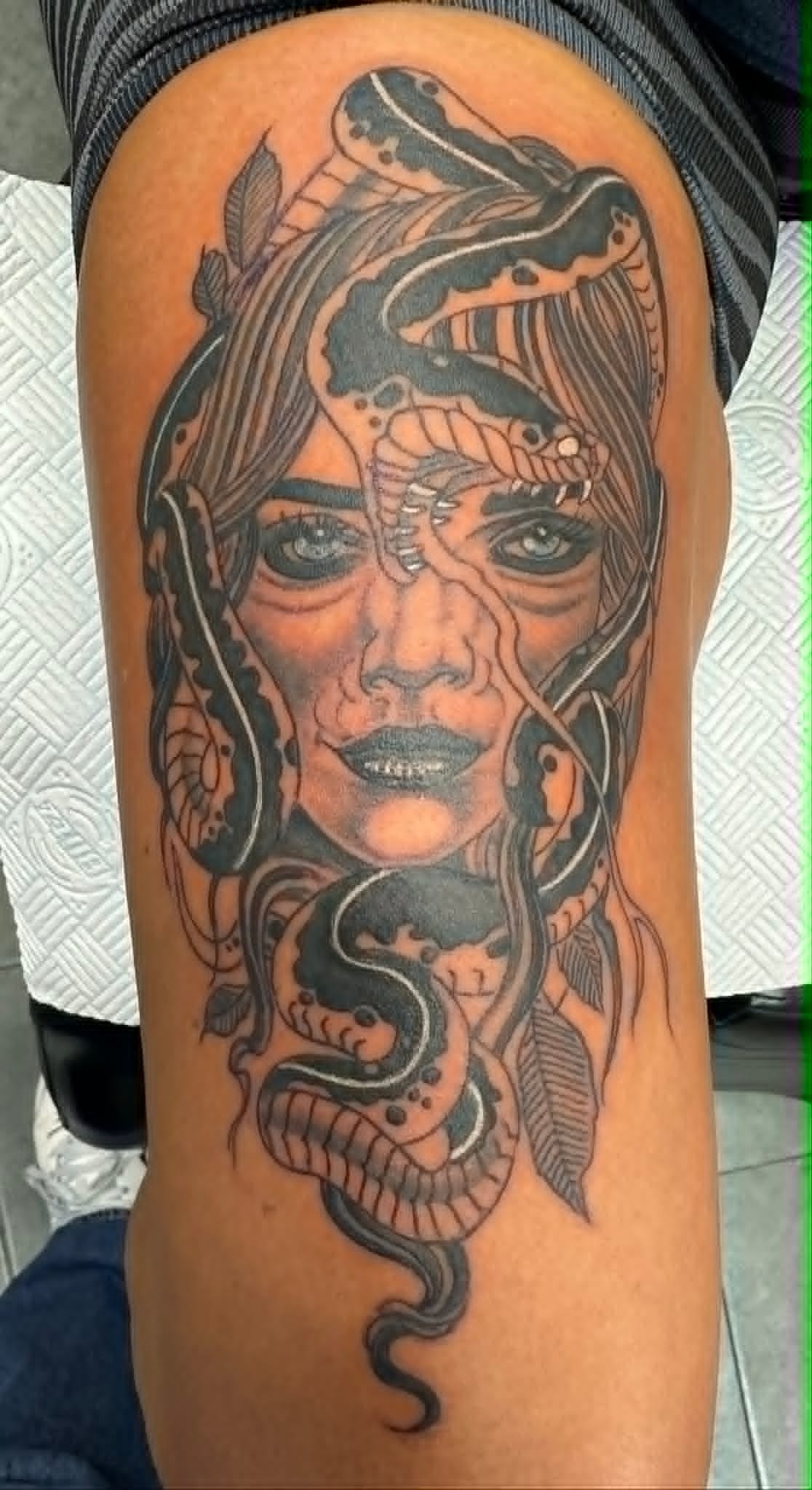 Black and grey Medusa portrait with serpents and leaves thigh tattoo by John Quinn at Tattoo Zone Newcastle.
