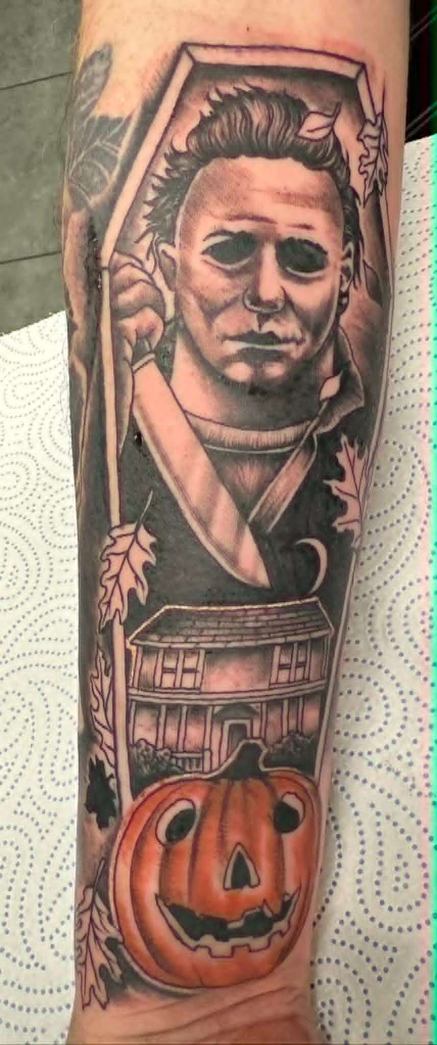 Custom Michael Myers Halloween portrait with haunted house and pumpkin tattoo on the arm by John Quinn at Tattoo Zone Newcastle.