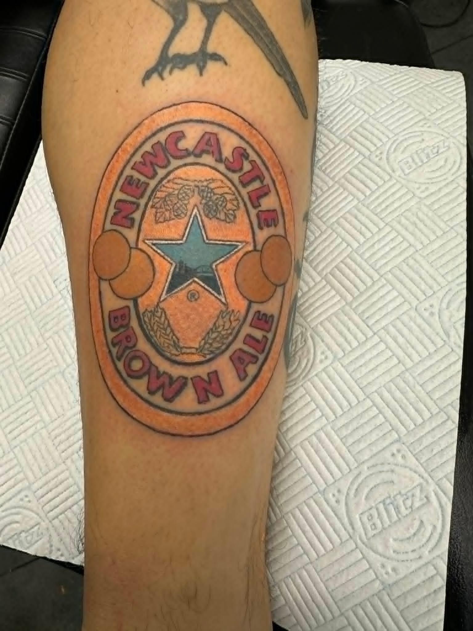 Traditional Newcastle Brown Ale bottle label tattoo on the leg by John Quinn at Tattoo Zone, tattoos Newcastle.