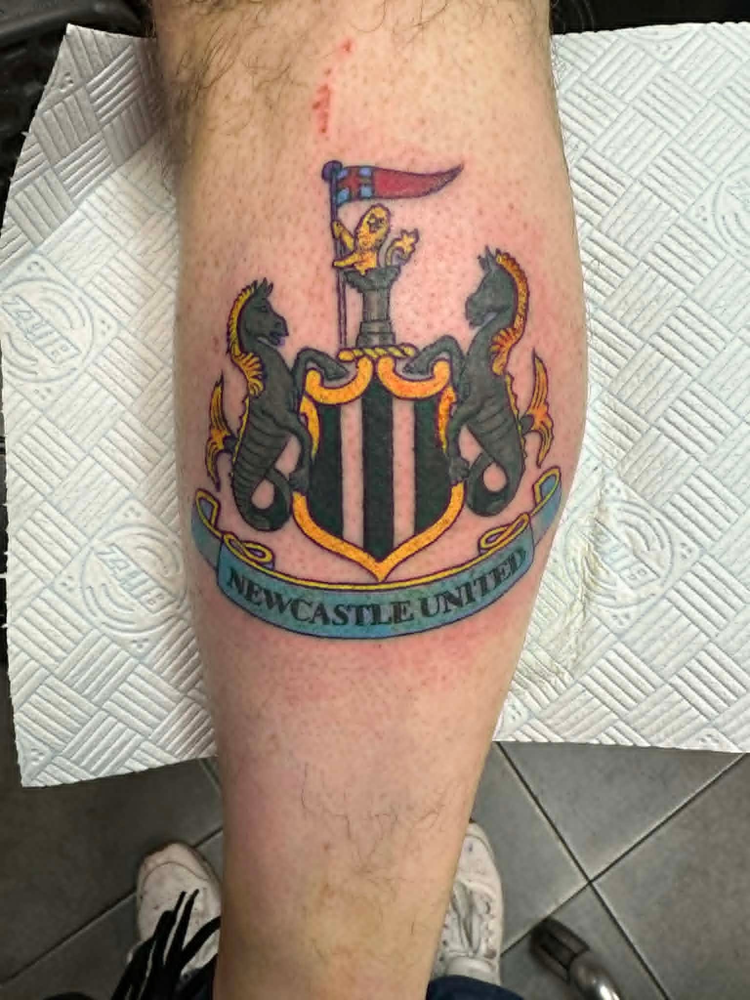 Newcastle United Football Club crest tattoo with seahorses and banner on the calf by John Quinn at Tattoo Zone Newcastle.