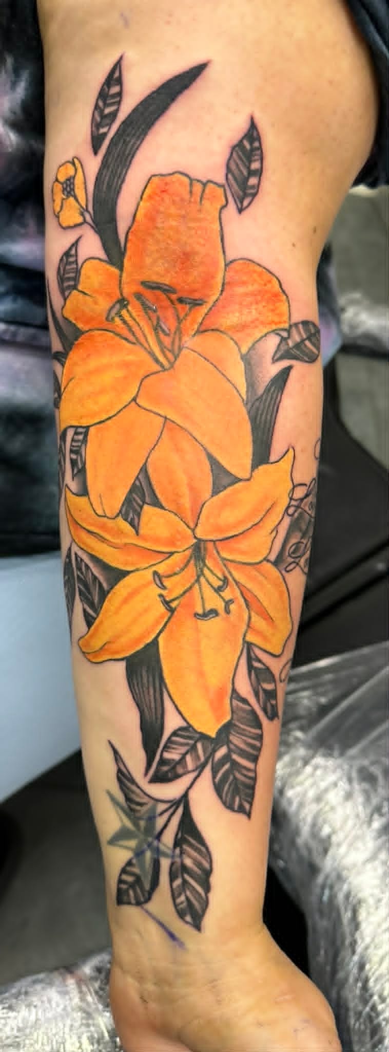 Custom orange lily flowers tattoo on the forearm by John Quinn at Tattoo Zone, tattoos Newcastle.