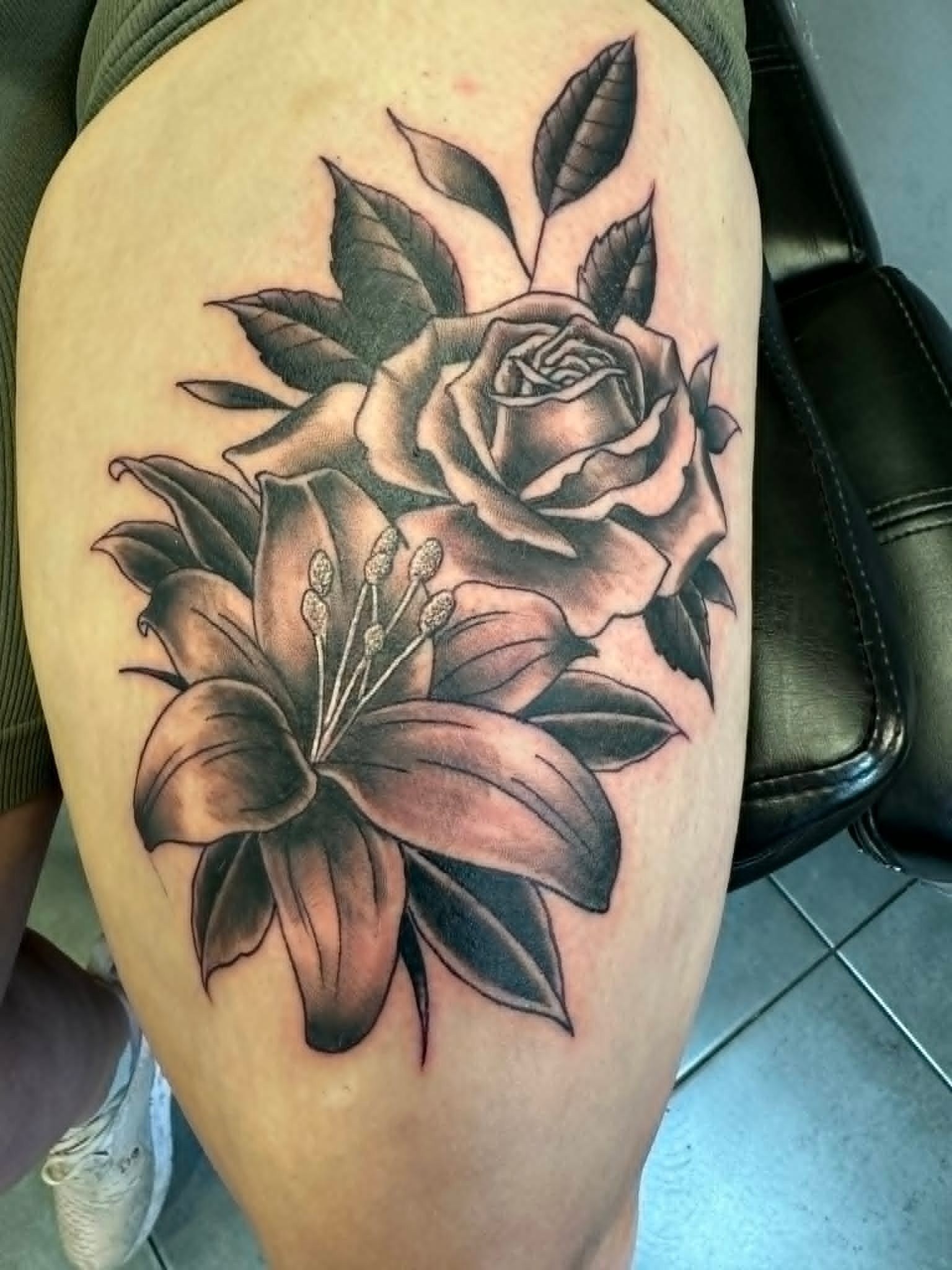 Black and grey rose and lily floral thigh tattoo by John Quinn at Tattoo Zone, tattoos Newcastle.