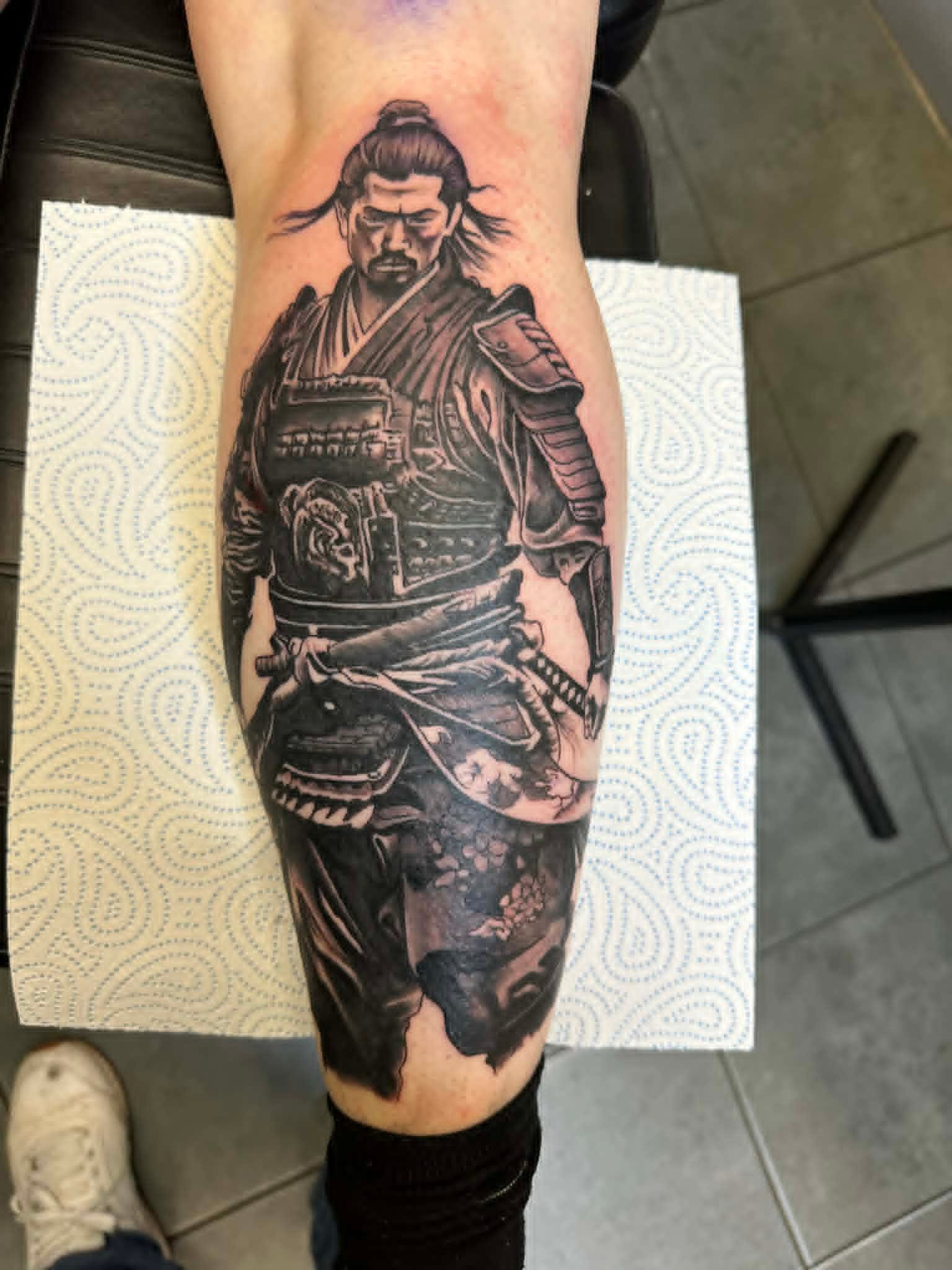 Realistic black and grey samurai warrior portrait on calf by John Quinn at Tattoo Zone, tattoos Newcastle.