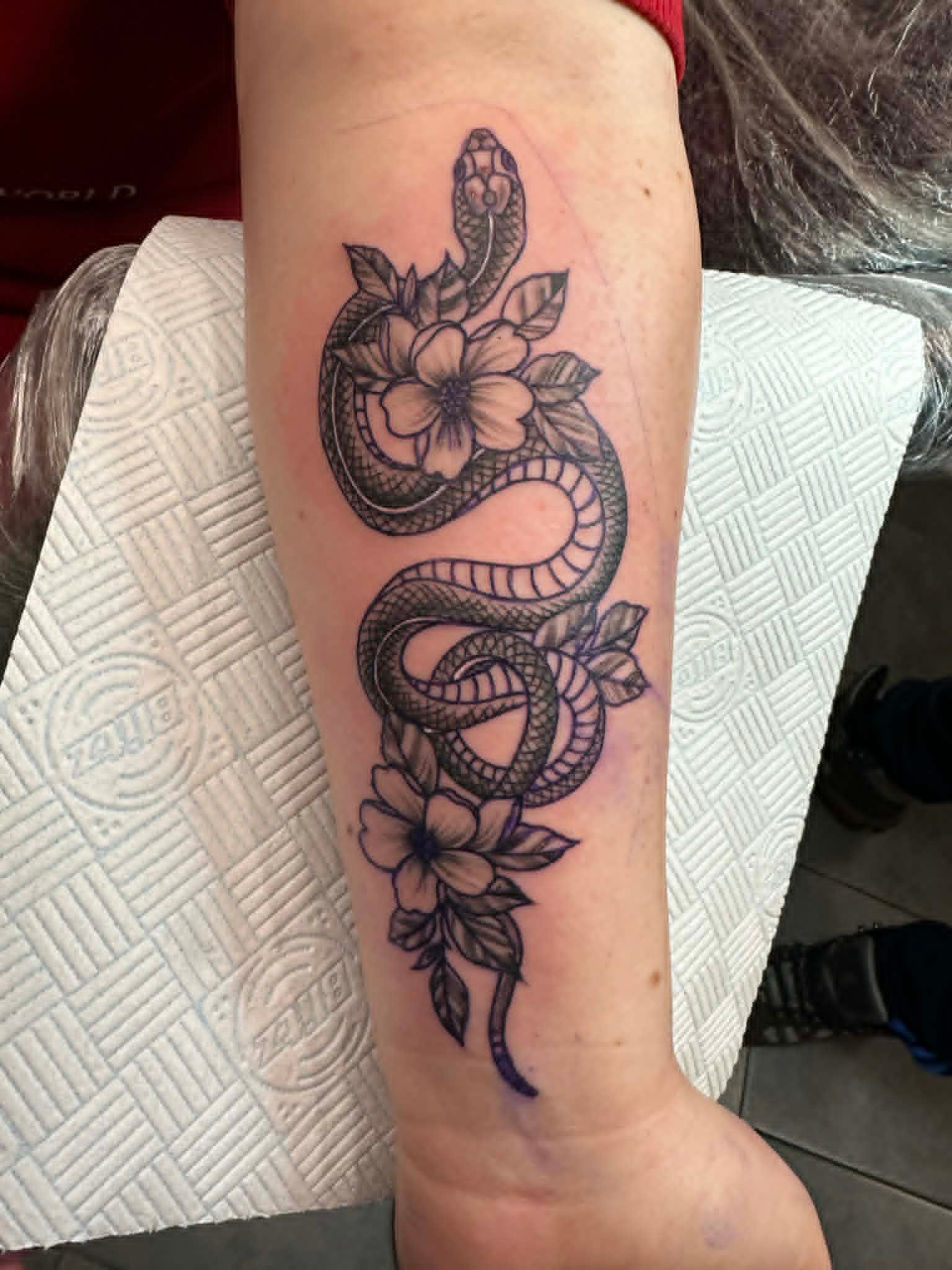 Fine line snake coiled with flowers on forearm by John Quinn at Tattoo Zone, tattoos Newcastle.