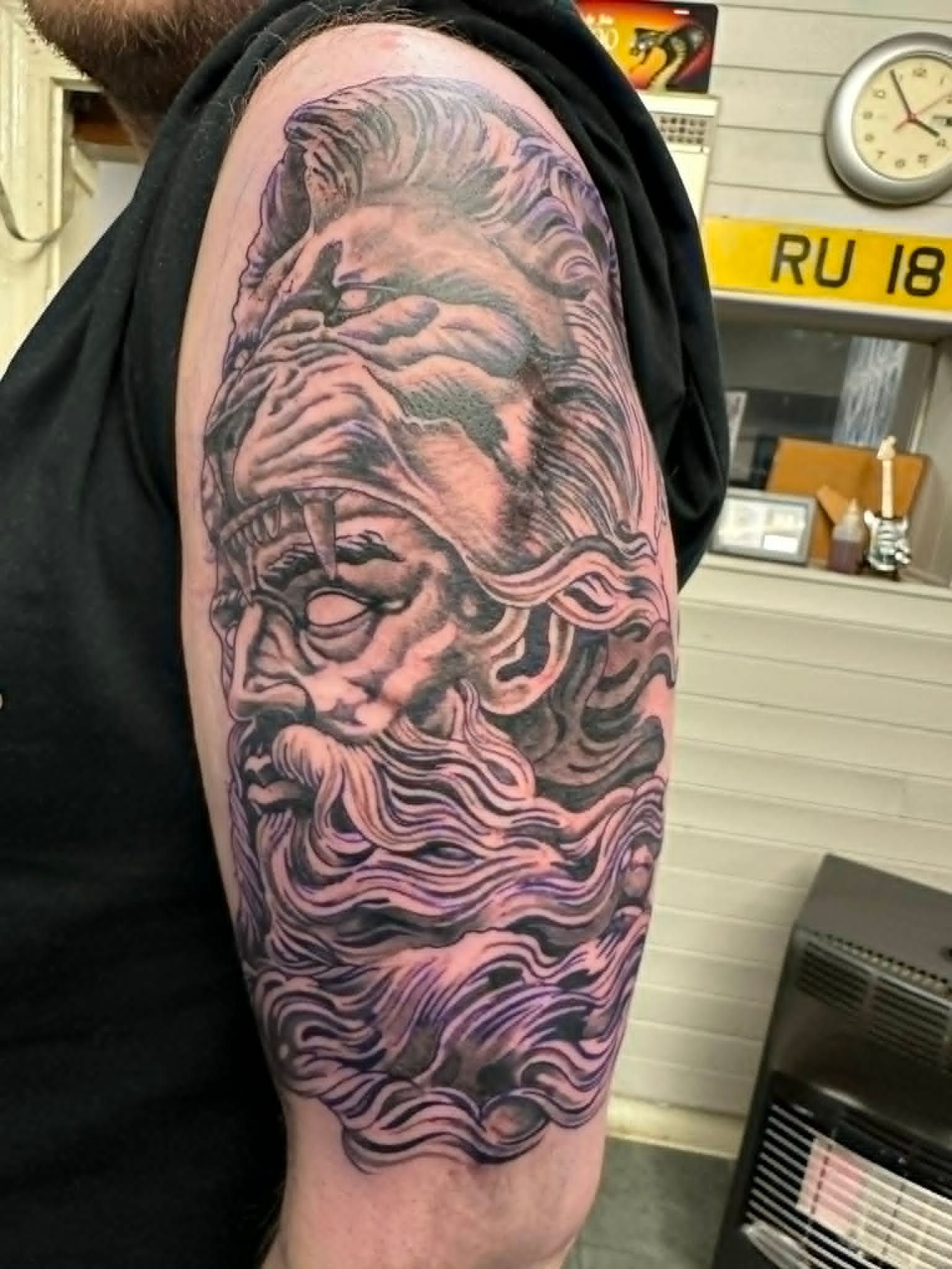 Black and grey Spartan warrior with helmet, lion crest and flowing beard upper arm tattoo by John Quinn at Tattoo Zone Newcastle.