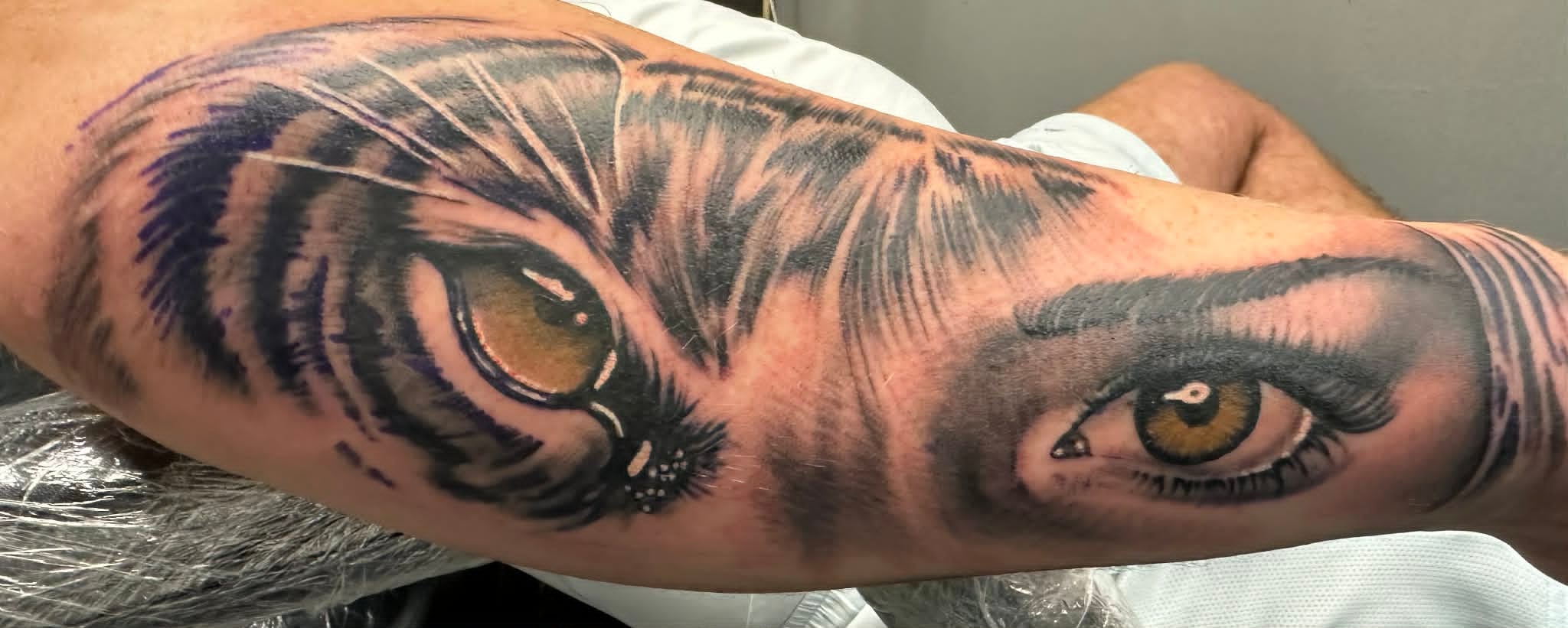 Realism tiger eye morphing into a female eye on the inner arm by John Quinn at Tattoo Zone, tattoos Newcastle.