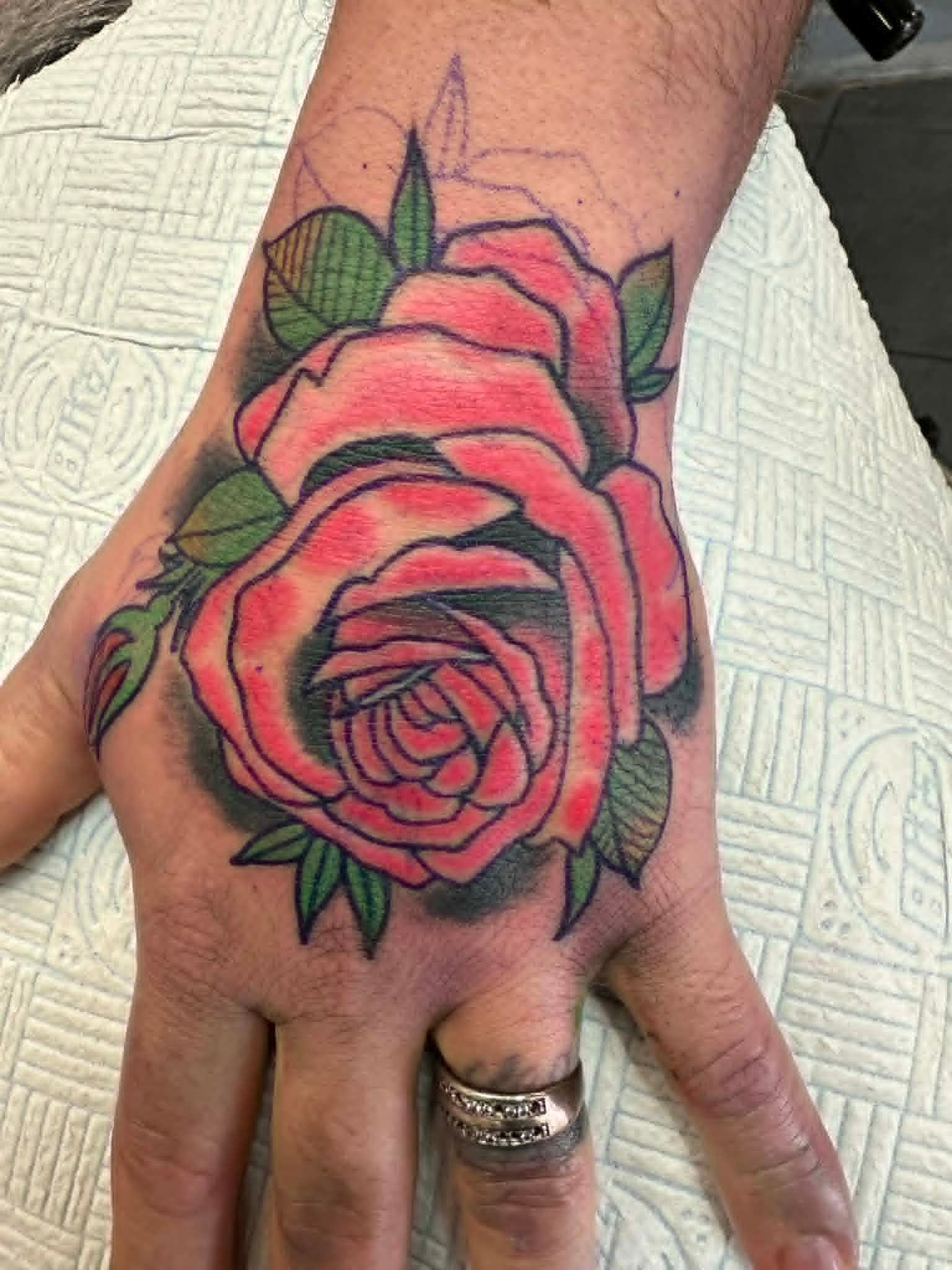 Traditional pink rose with green leaves on hand by John Quinn at Tattoo Zone, tattoos Newcastle.