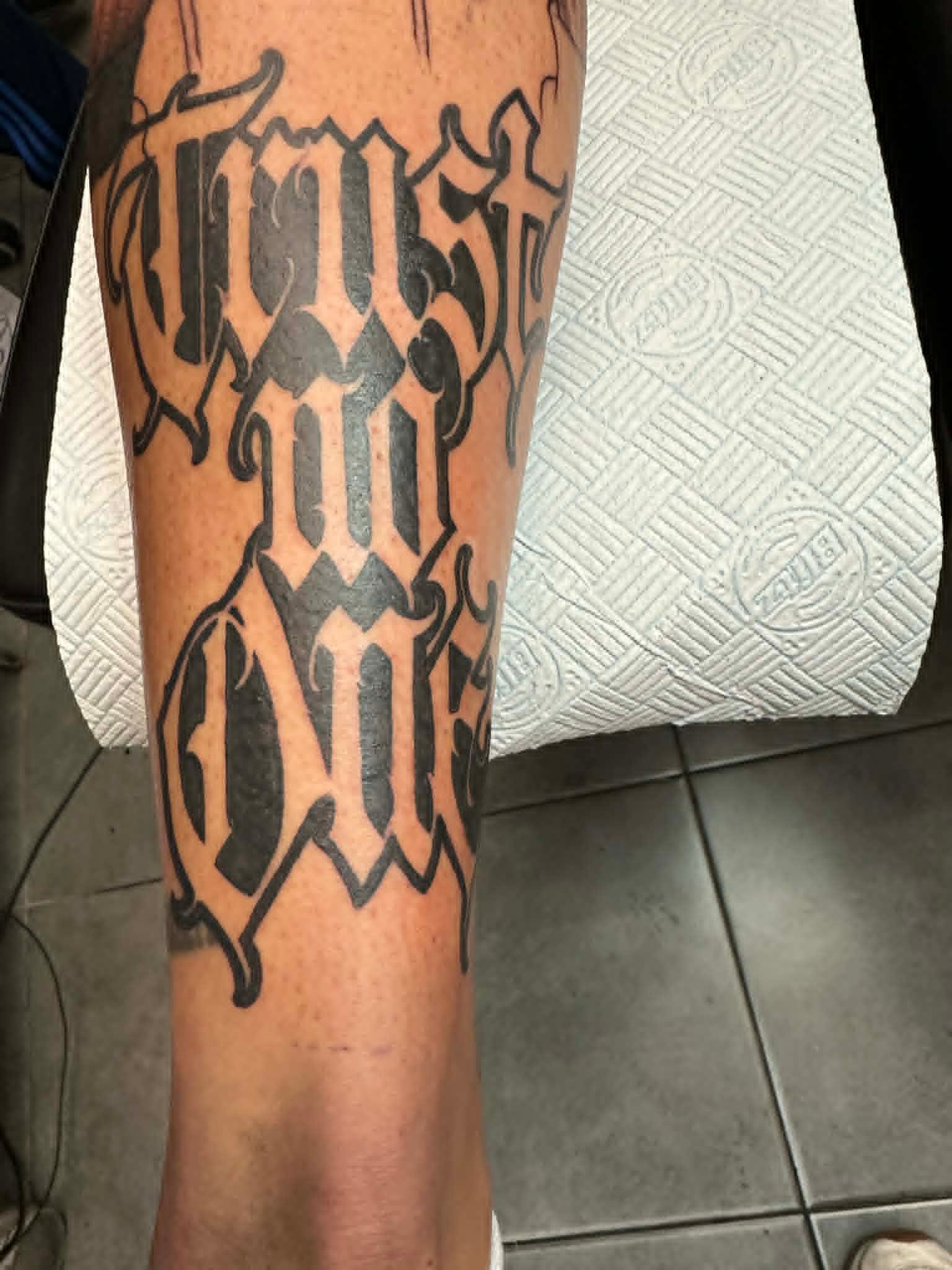 Custom Trust No One ambigram lettering tattoo on the forearm by John Quinn at Tattoo Zone, tattoos Newcastle.