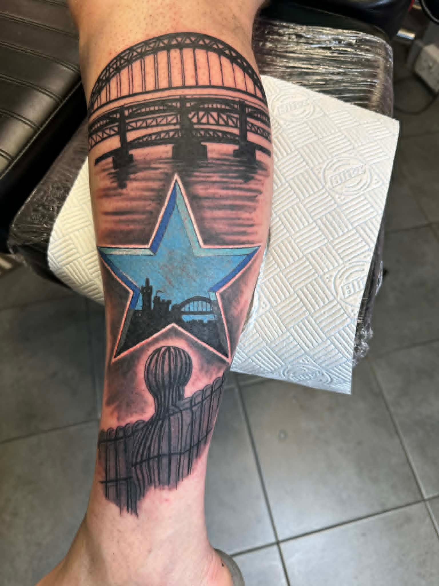 Tyne Bridge Angel of the North and Newcastle blue star leg tattoo by John Quinn at Tattoo Zone, tattoos Newcastle.