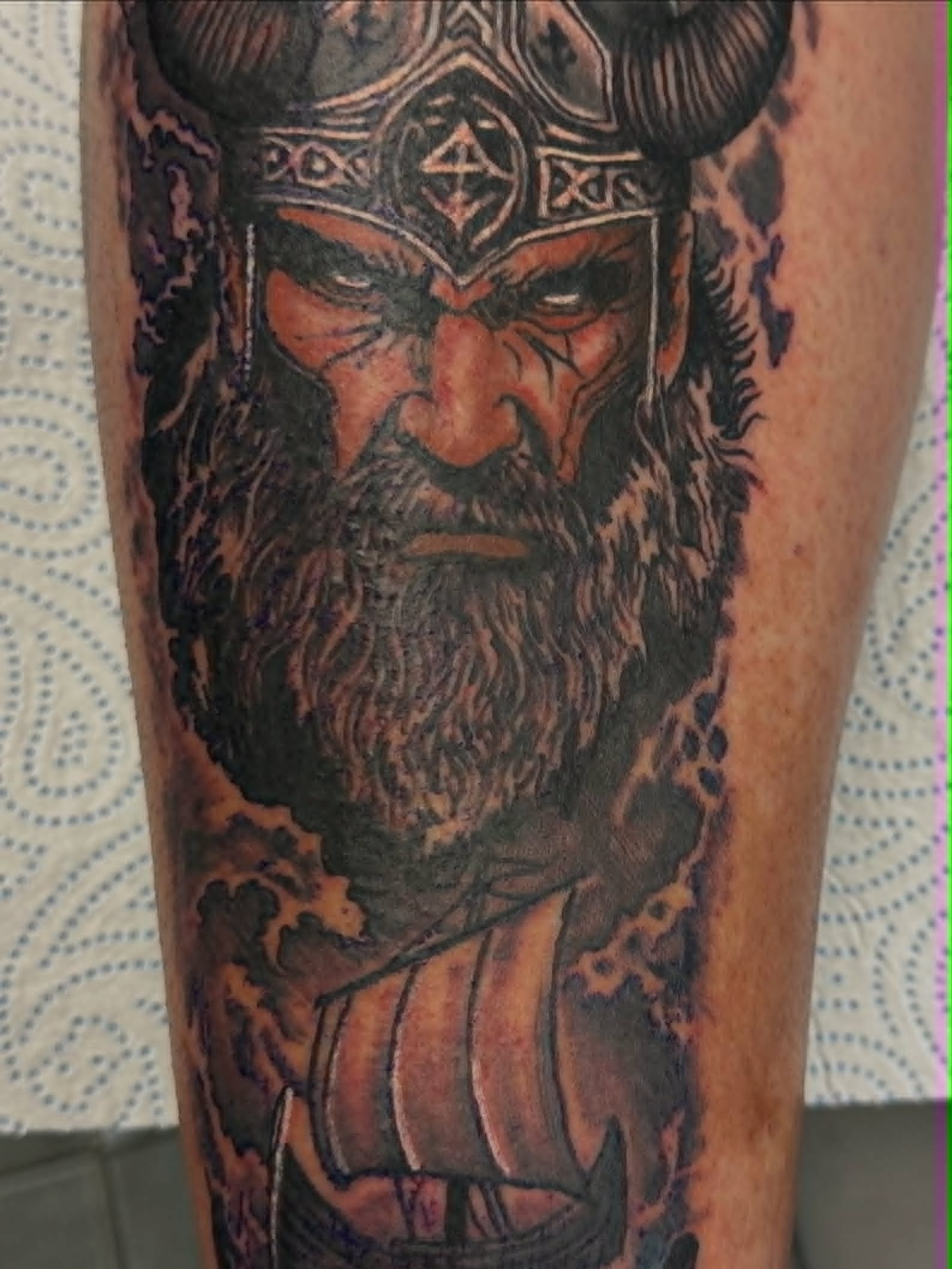 Realism Viking warrior portrait with horned helmet, full beard and longship below calf tattoo by John Quinn at Tattoo Zone Newcastle.