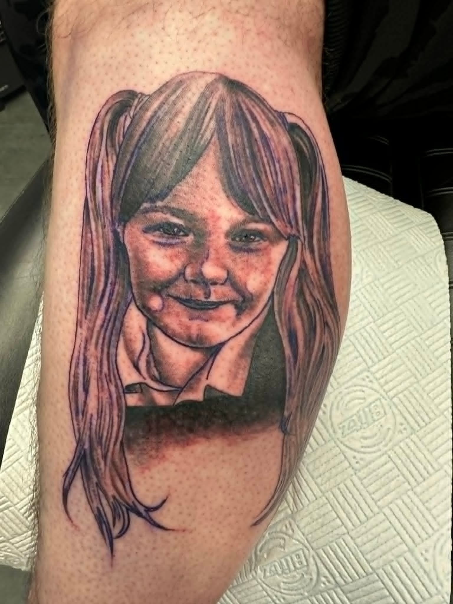 Realism portrait of young girl with pigtails in school uniform calf tattoo by John Quinn at Tattoo Zone Newcastle.