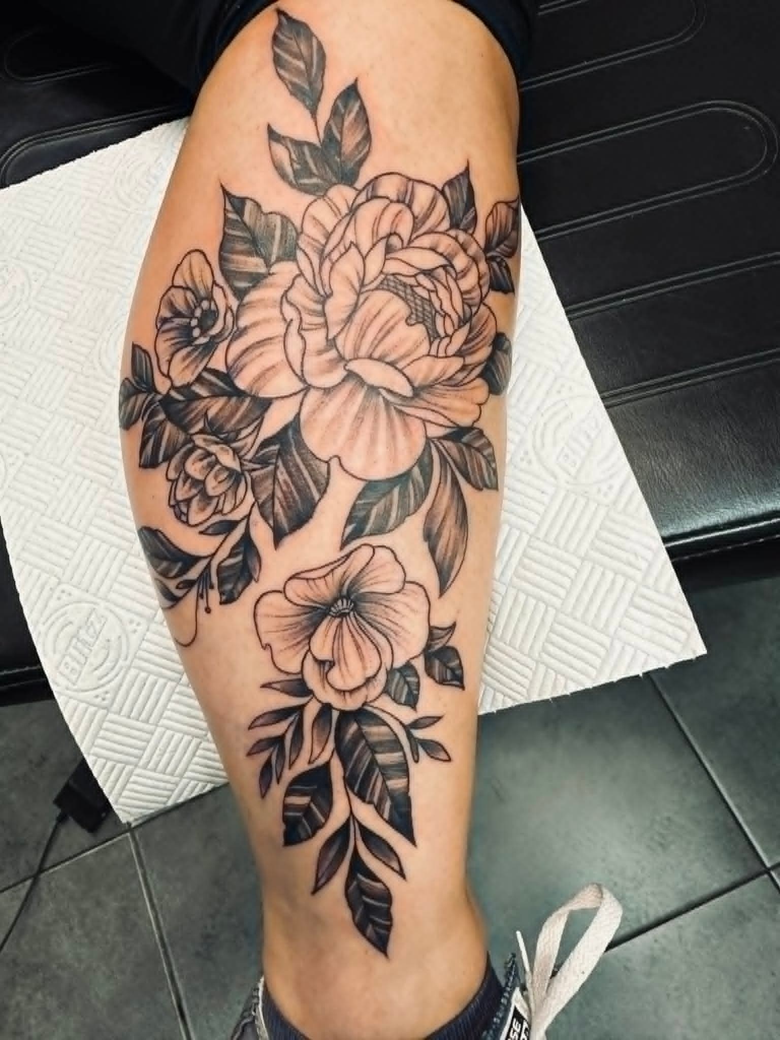 Black and grey peony and floral bouquet tattoo on the calf by John Quinn at Tattoo Zone Newcastle.