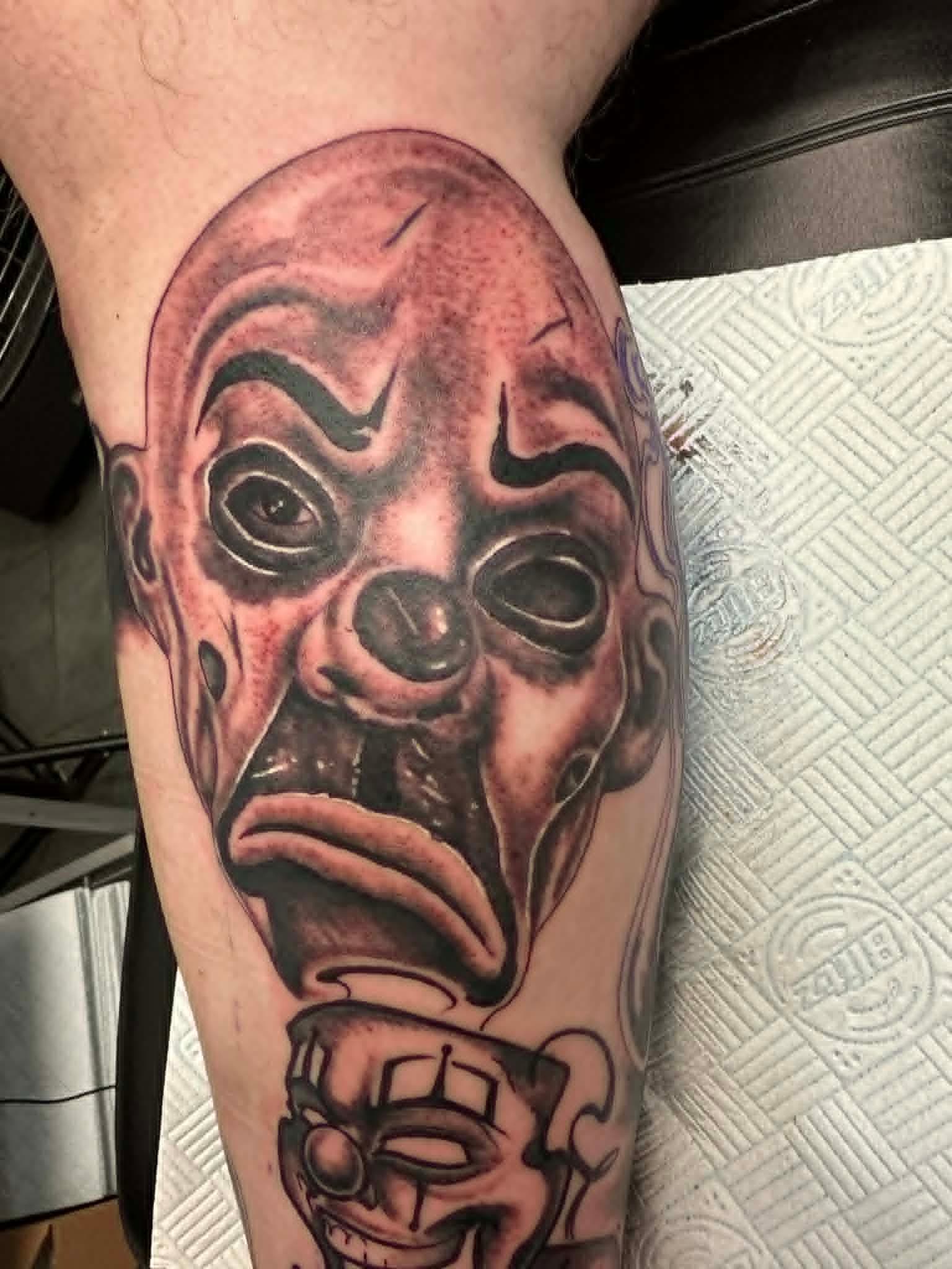 Black and grey chicano clown faces on calf by John Quinn at Tattoo Zone, tattoos Newcastle.
