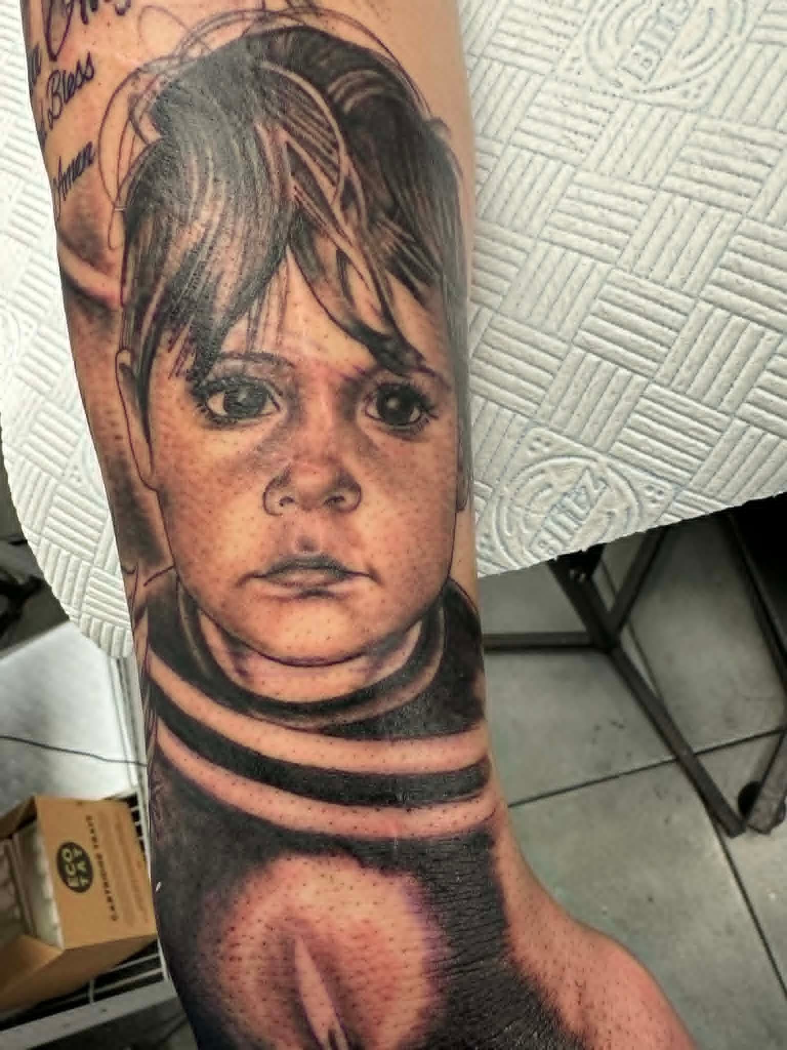 Realism child portrait with Newcastle United stripes on the forearm by John Quinn at Tattoo Zone, tattoos Newcastle.